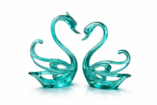 Two green glass swan figures on a white background